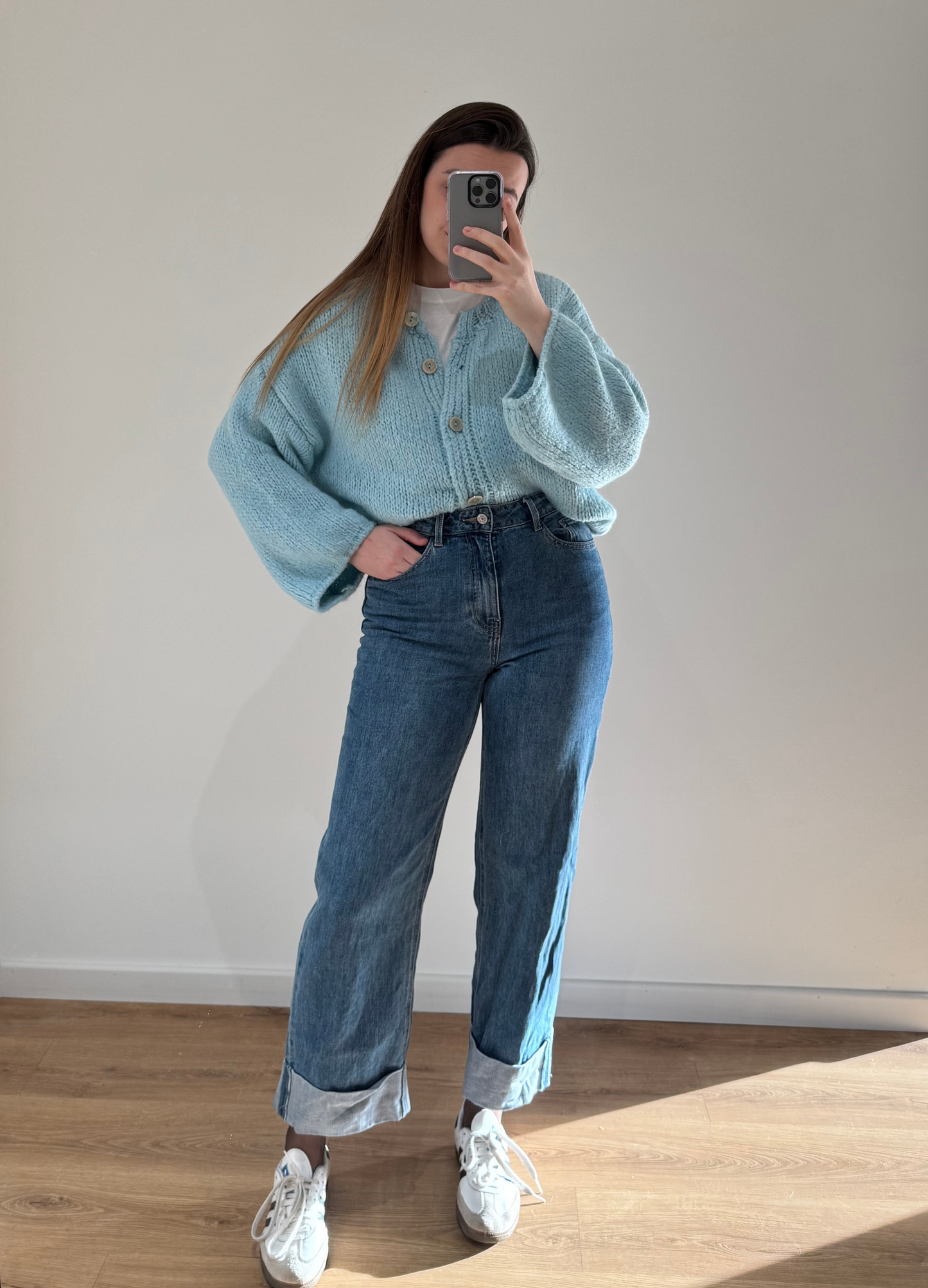 Femme portant un gilet droit bleu LOU en coton à boutons argenté, avec un jean droit à ourlets ALEXIA, vue en intérieur sur parquet et fond blanc.