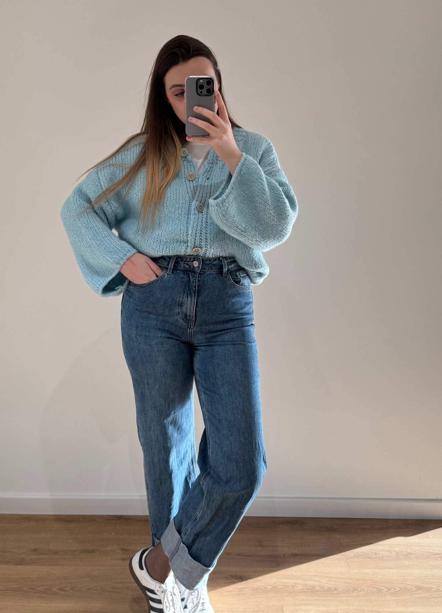 Femme portant un gilet droit bleu LOU en coton à boutons argenté, avec un jean droit à ourlets ALEXIA, vue en intérieur sur parquet et fond blanc.