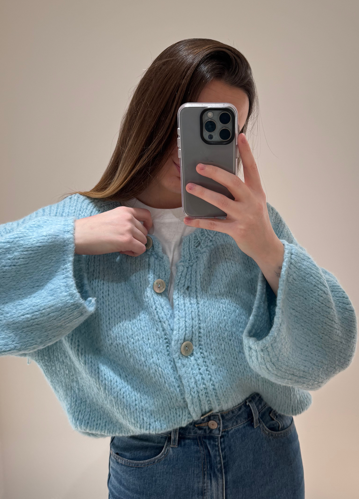 Zoom sur une femme portant un gilet droit bleu LOU en coton à boutons argenté, avec un jean droit à ourlets ALEXIA, vue en intérieur sur parquet et fond blanc.
