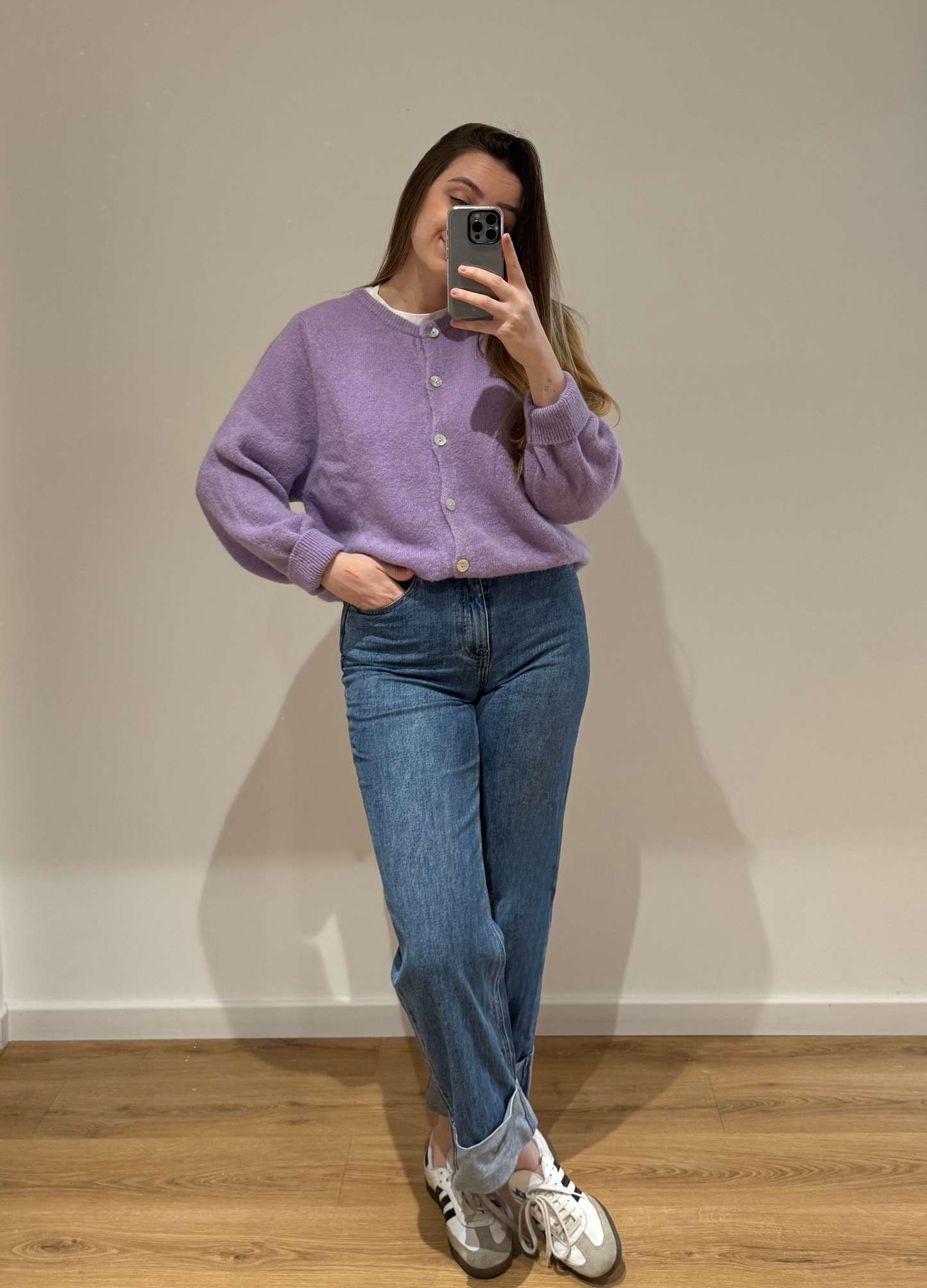 Femme portant un cardigan lila OLIVIA en coton à boutons argenté, avec un jean droit ALEXIA à ourlet , vue en intérieur sur parquet et fond blanc.