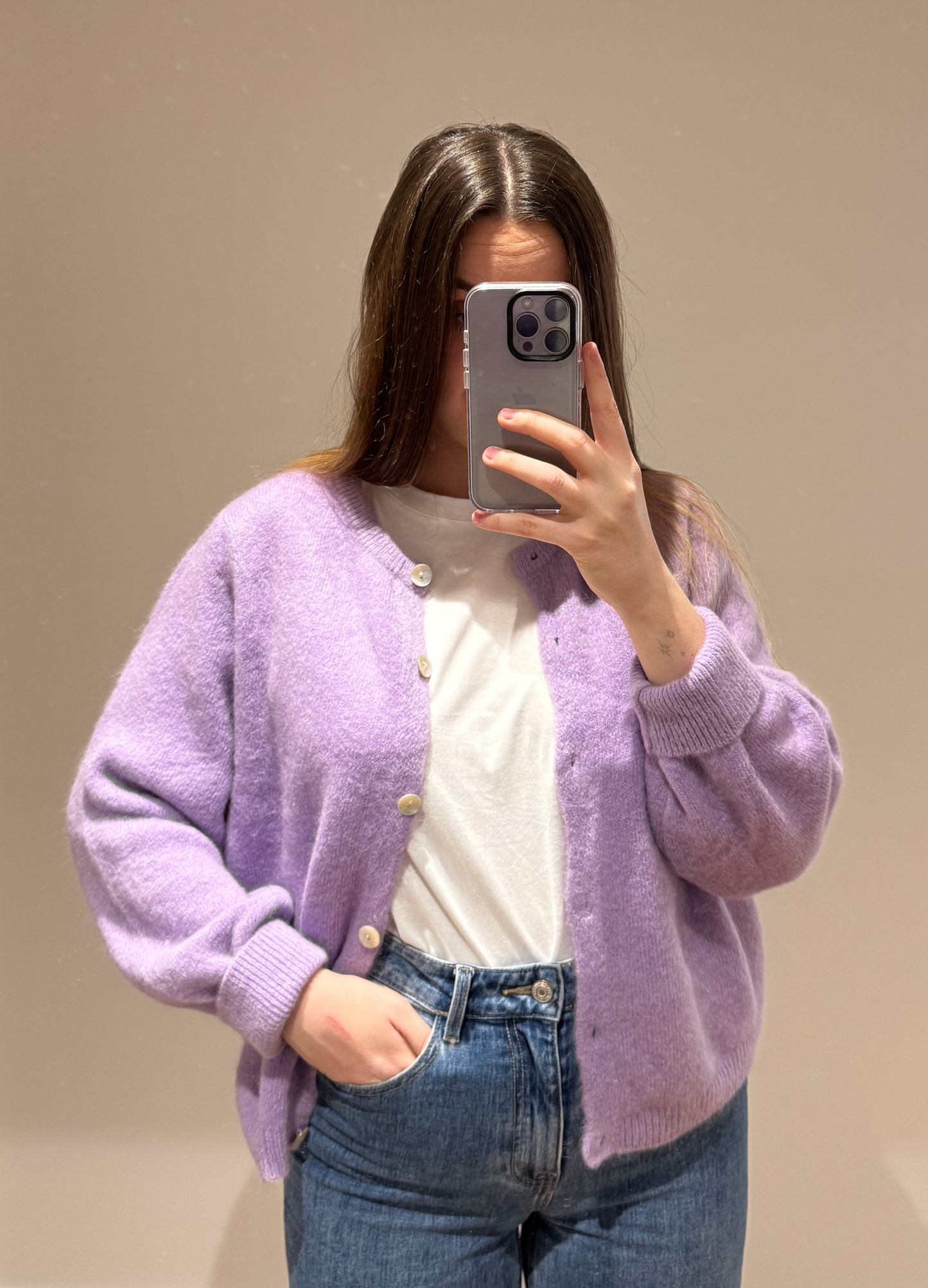 Zoom sur un cardigan lila OLIVIA avec des boutons argentés, porté avec un t-shirt blanc CECILE en dessous et un jean ALEXIA, sur un fond blanc.