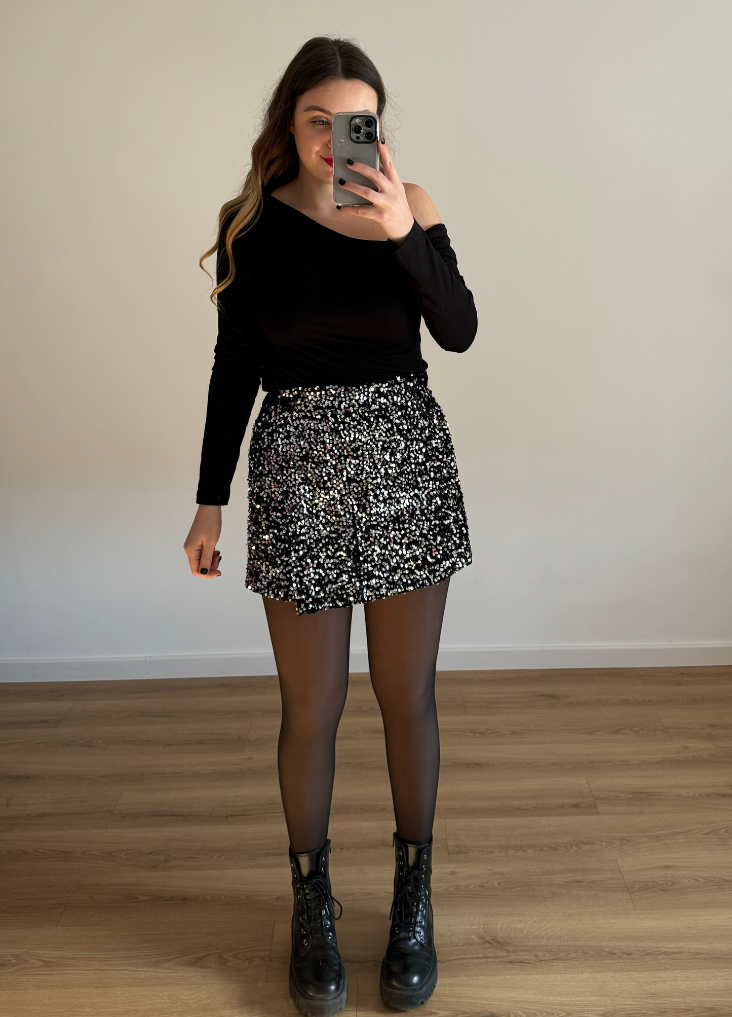 Femme posant en selfie, portant un short noir orné de strass étincelants, assorti à un haut élégant. Look glamour et moderne, parfait pour une soirée ou un événement spécial.
