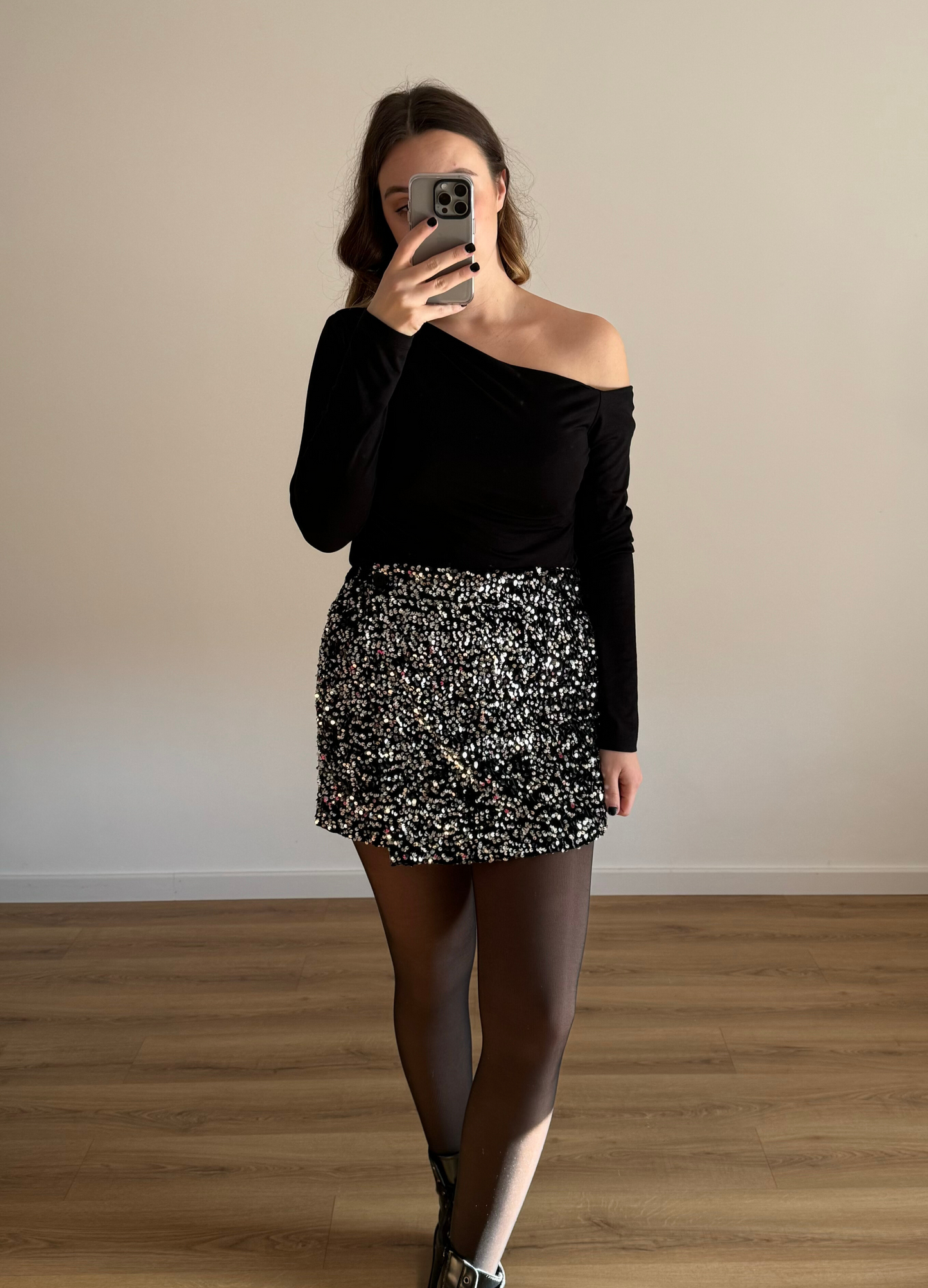 Femme posant en selfie, portant un short noir orné de strass étincelants, assorti à un haut élégant. Look glamour et moderne, parfait pour une soirée ou un événement spécial.