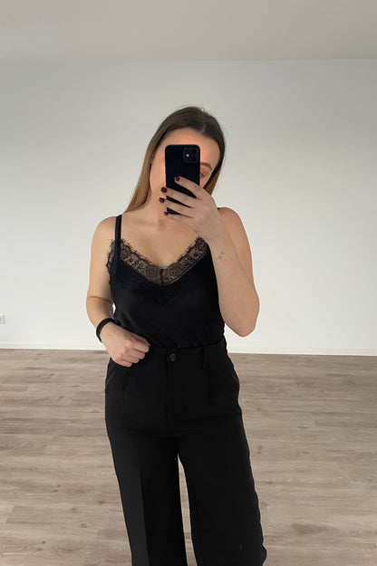 Une fille qui porte un caraco noir avec un pantalon de costume noir