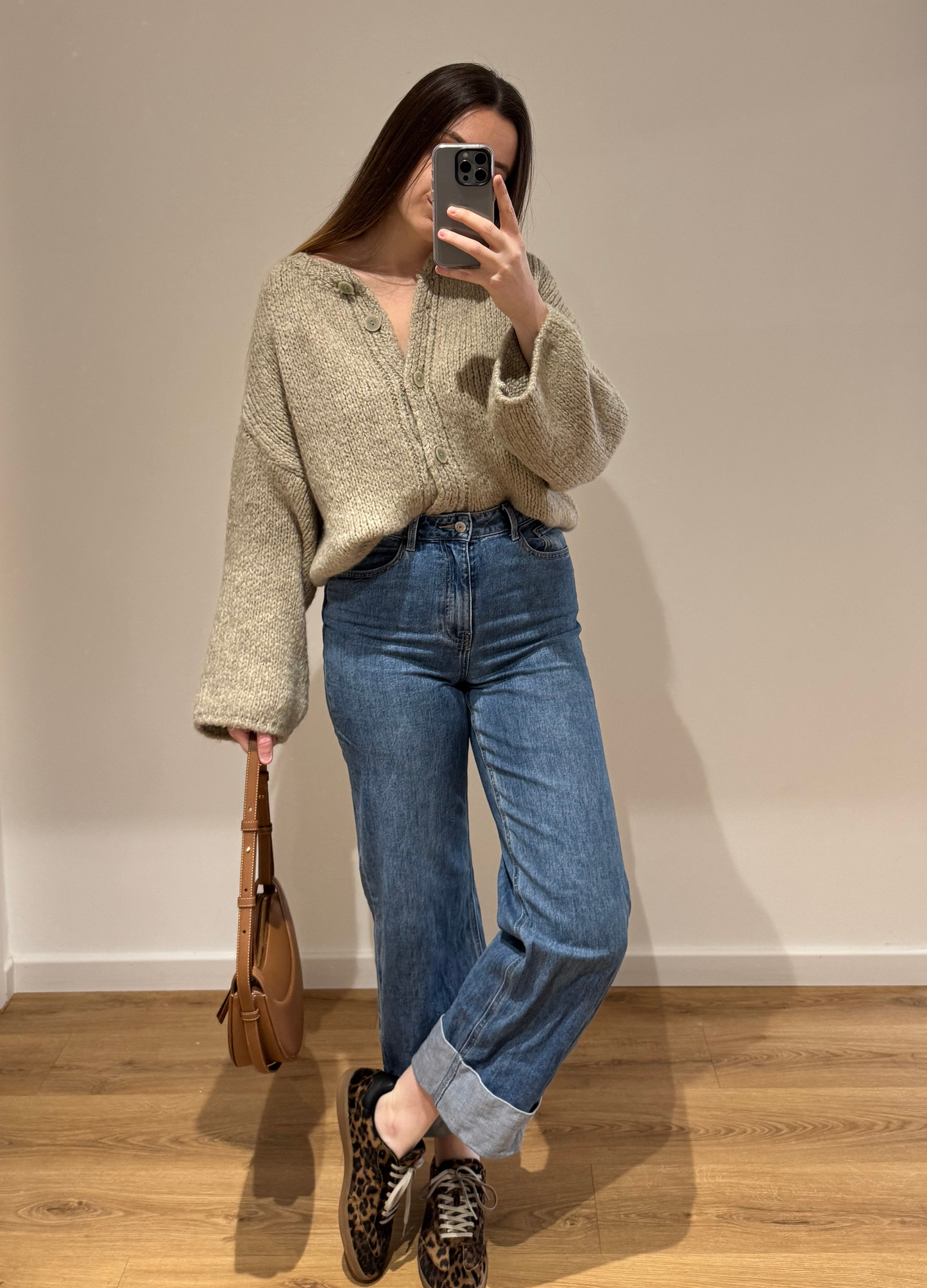 Femme portant un gilet droit beige LOU en coton à boutons argenté, avec un jean droit à ourlets ALEXIA, vue en intérieur sur parquet et fond blanc.