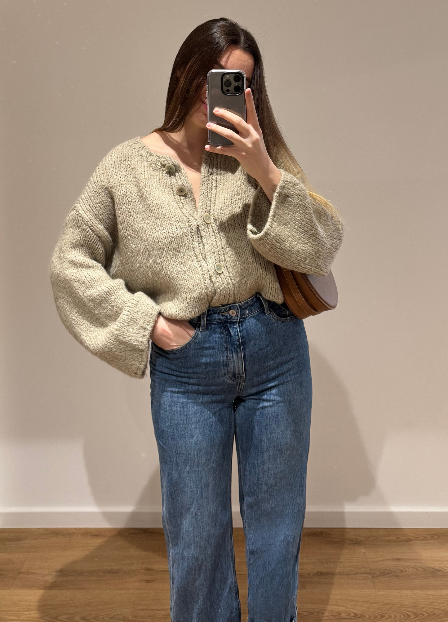 Femme portant un gilet droit beige LOU en coton à boutons argenté, avec un jean droit à ourlets ALEXIA, vue en intérieur sur parquet et fond blanc.