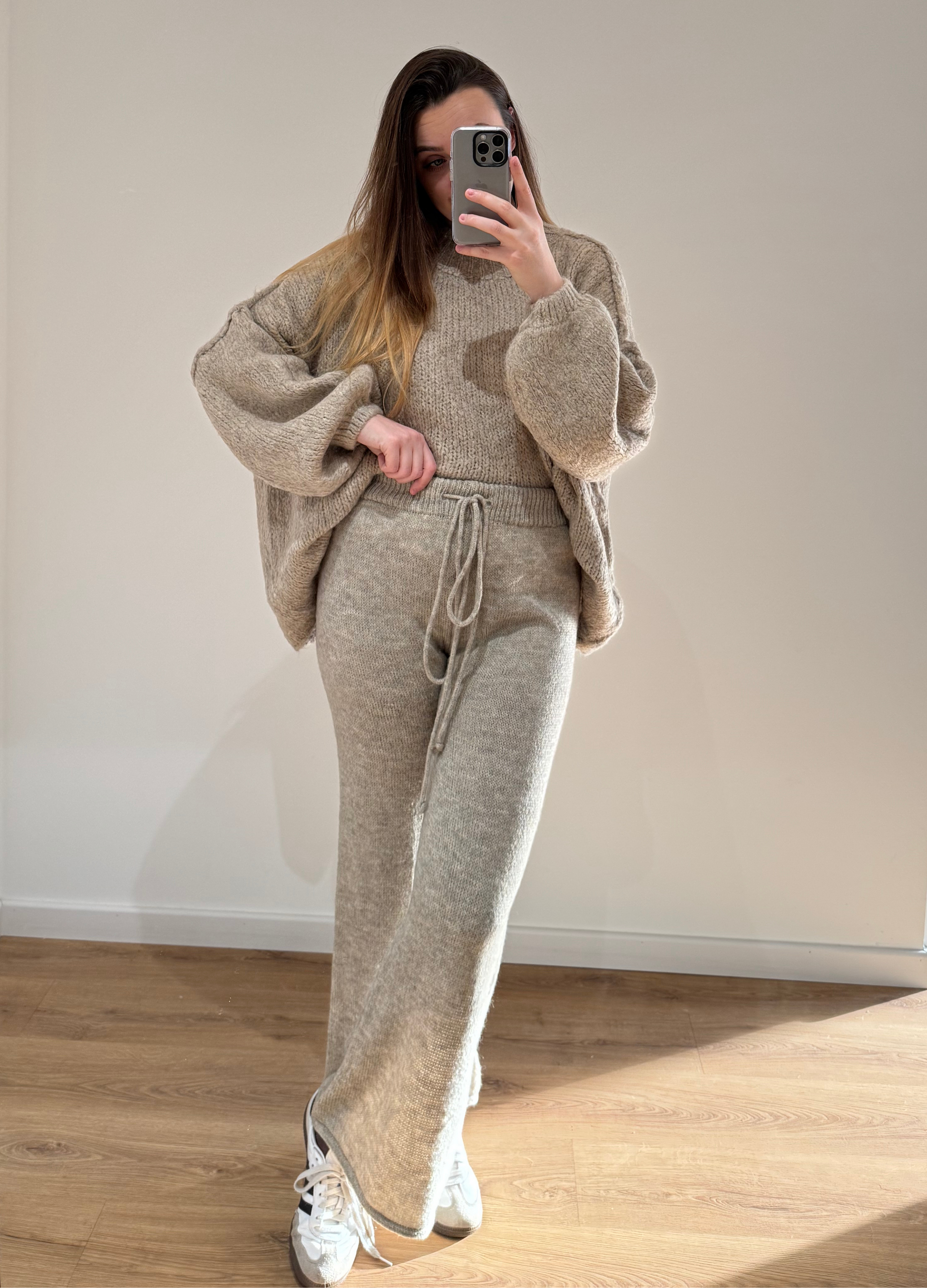 Femme habillée en ensemble beige en maille avec pull ample ANGELIQUE et pantalon large LEANA beige, posant dans une pièce lumineuse.