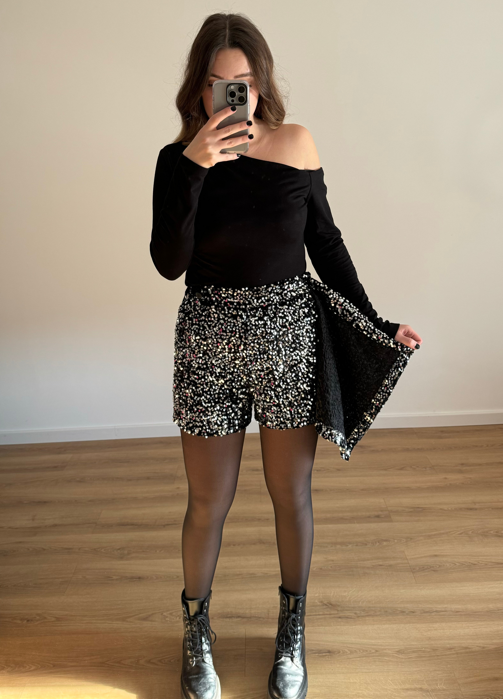 Femme posant en selfie, portant un short noir orné de strass étincelants, assorti à un haut élégant. Look glamour et moderne, parfait pour une soirée ou un événement spécial. 