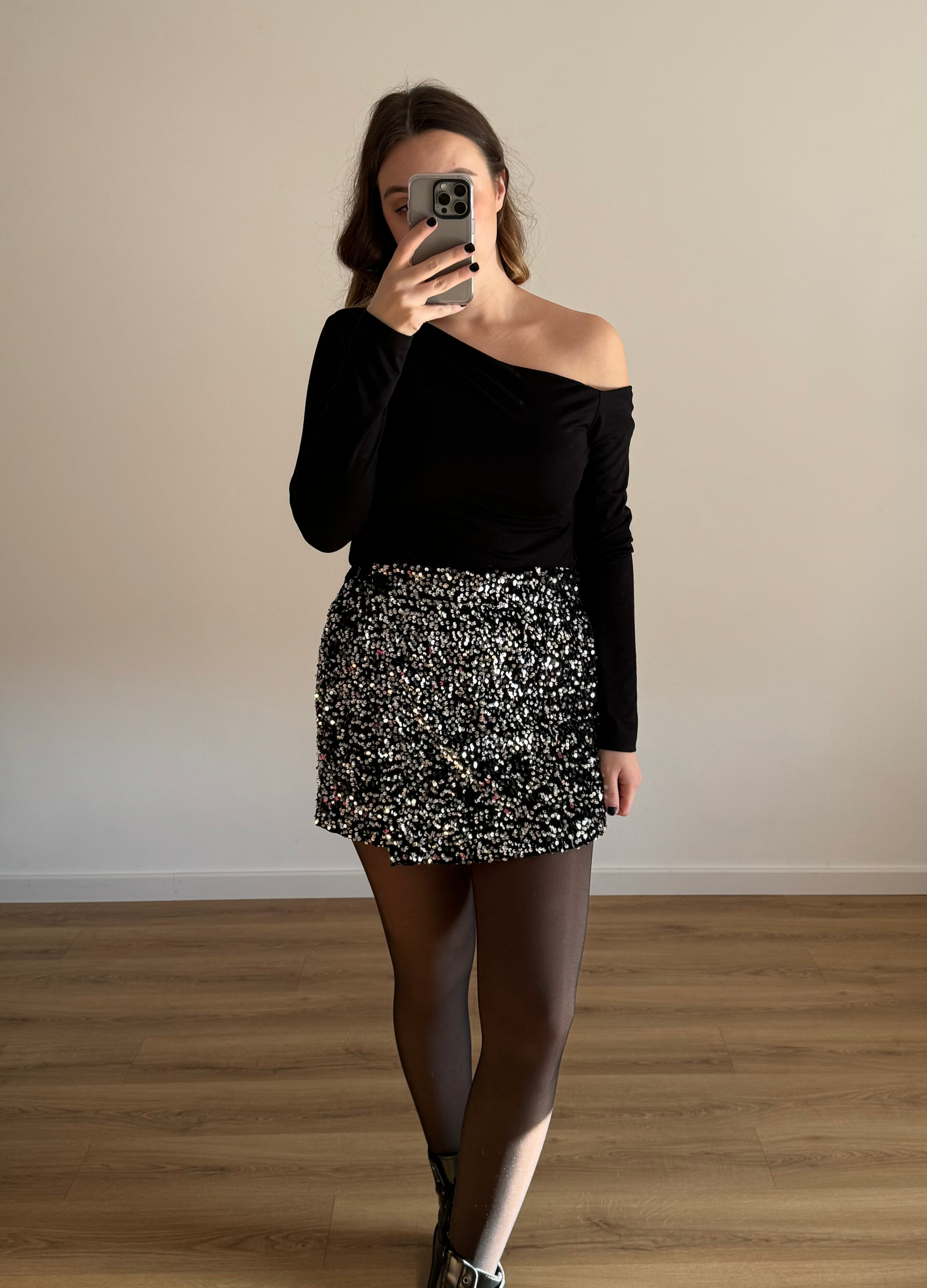 Femme posant en selfie, portant un short noir orné de strass étincelants, assorti à un haut élégant. Look glamour et moderne, parfait pour une soirée ou un événement spécial. 