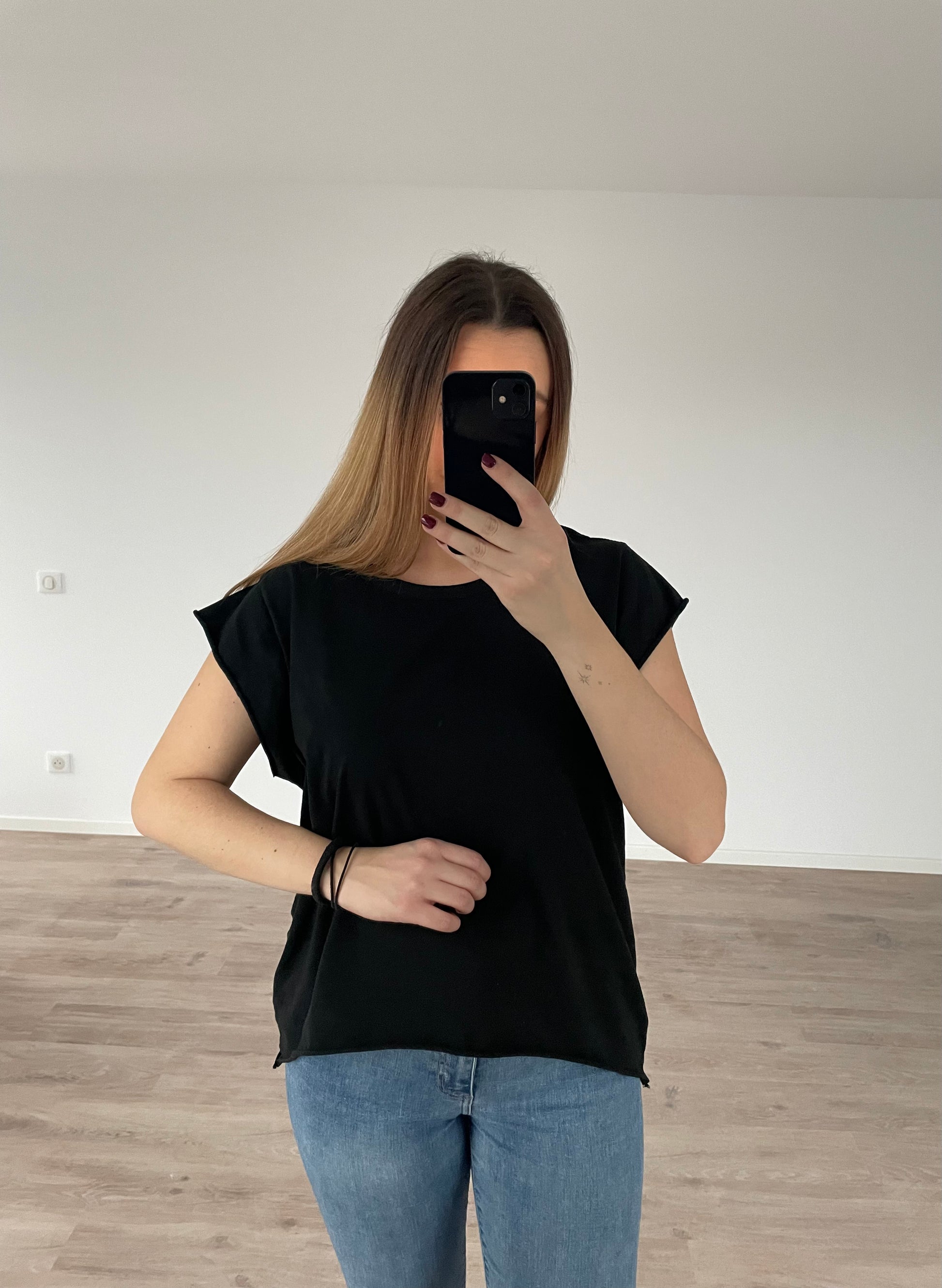 Une fille qui porte un top noir en matière 100 % Coton avec un jean bleu